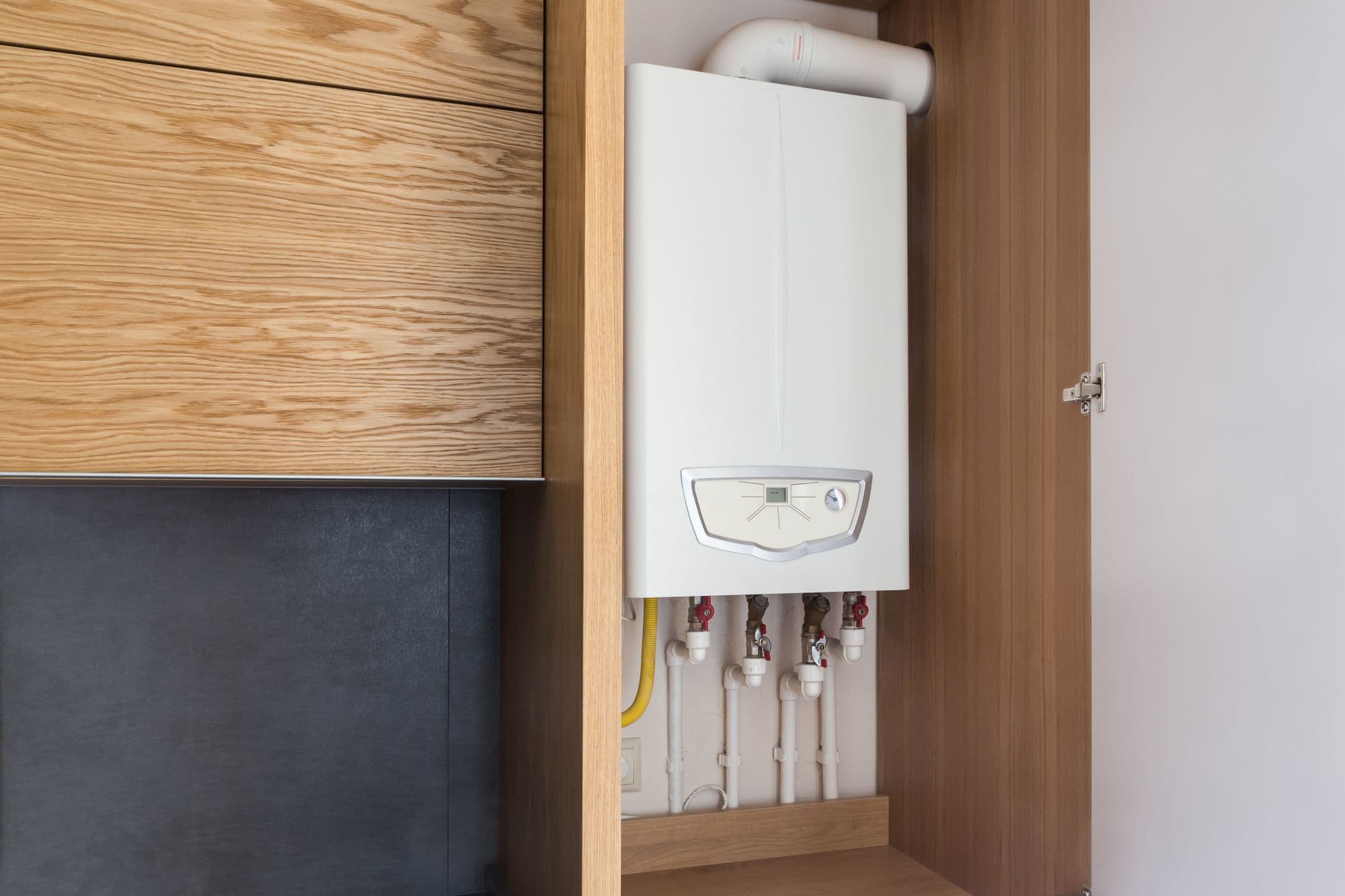 White combi boiler neatly fitted in a timber kitchen cupboard