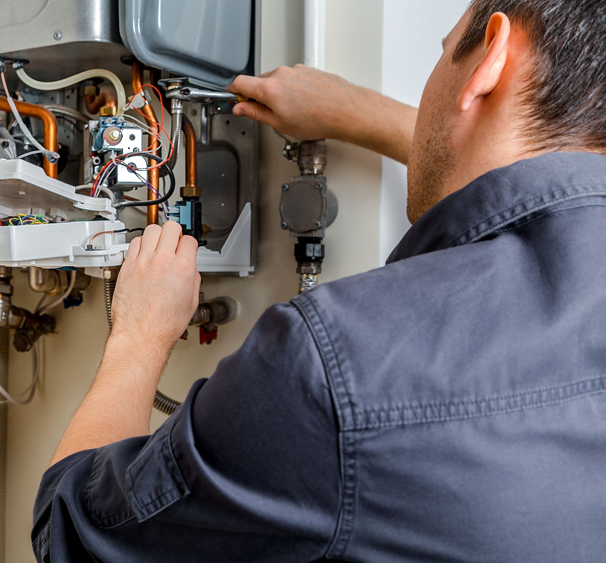 Gas engineer working inside an open boiler during a repair