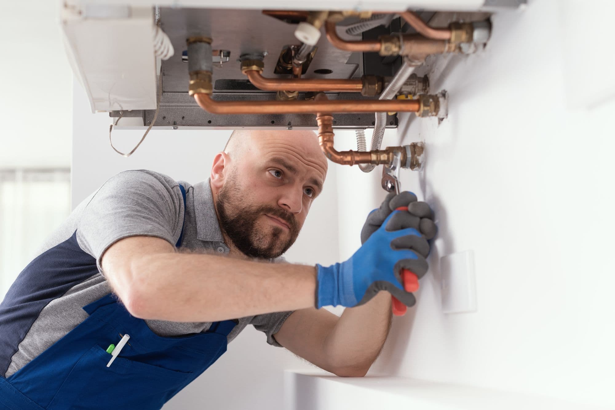 Engineer tightening copper pipework under a newly fitted combi boiler